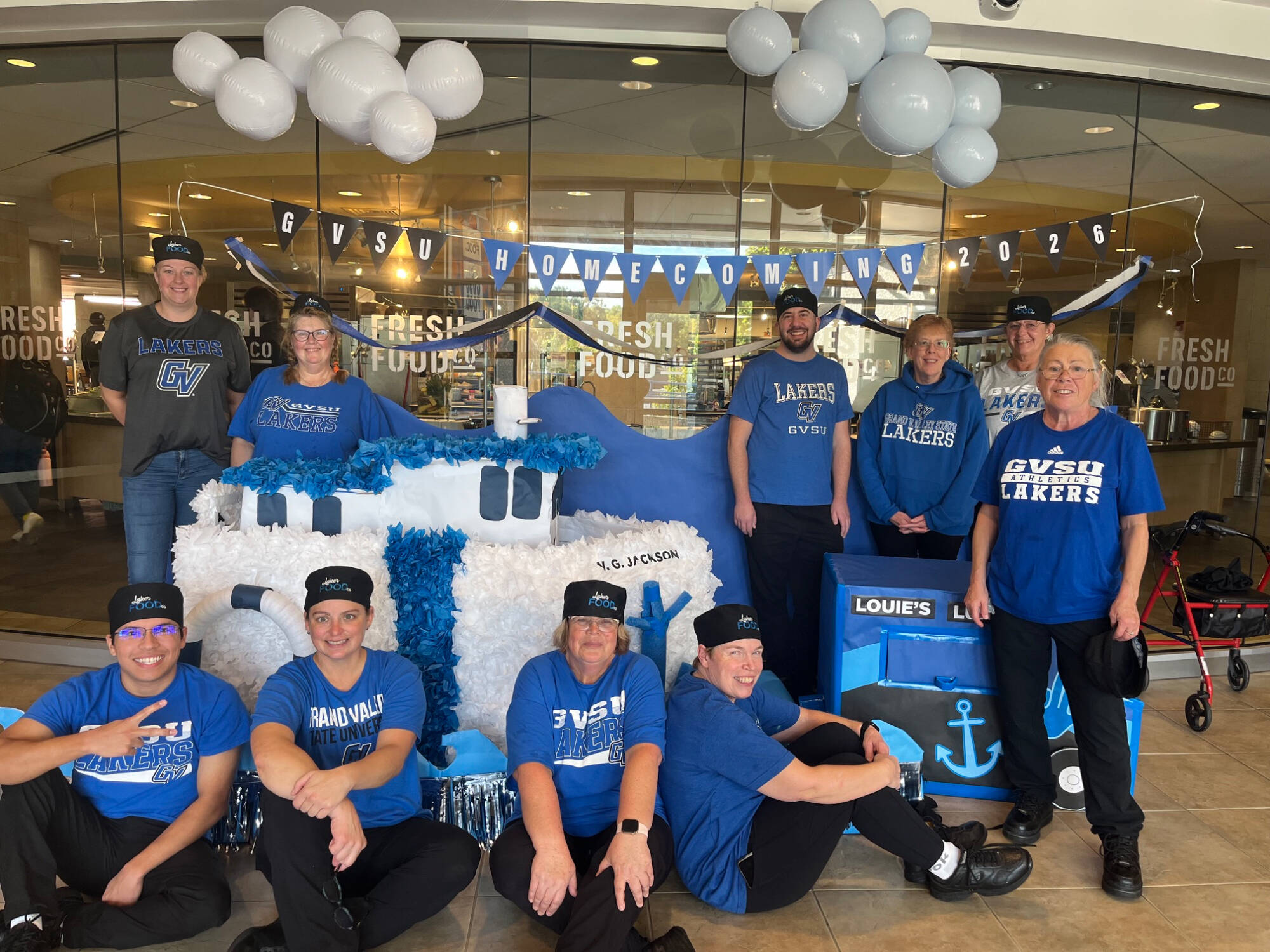 Group of individuals in front of homecoming decorations